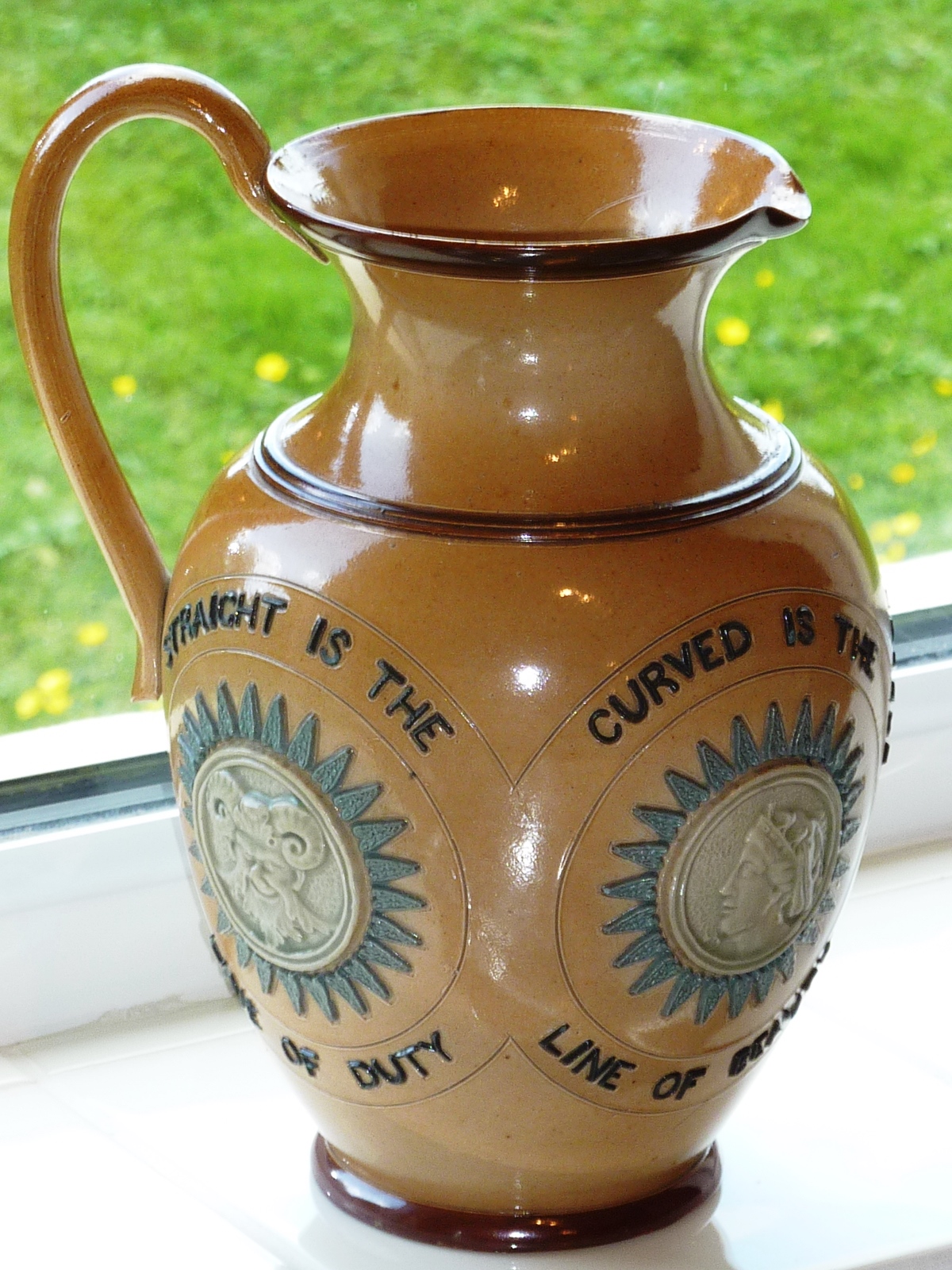 A Doulton Lambeth salt glaze stoneware Jug with applied mask roundel appliques and various