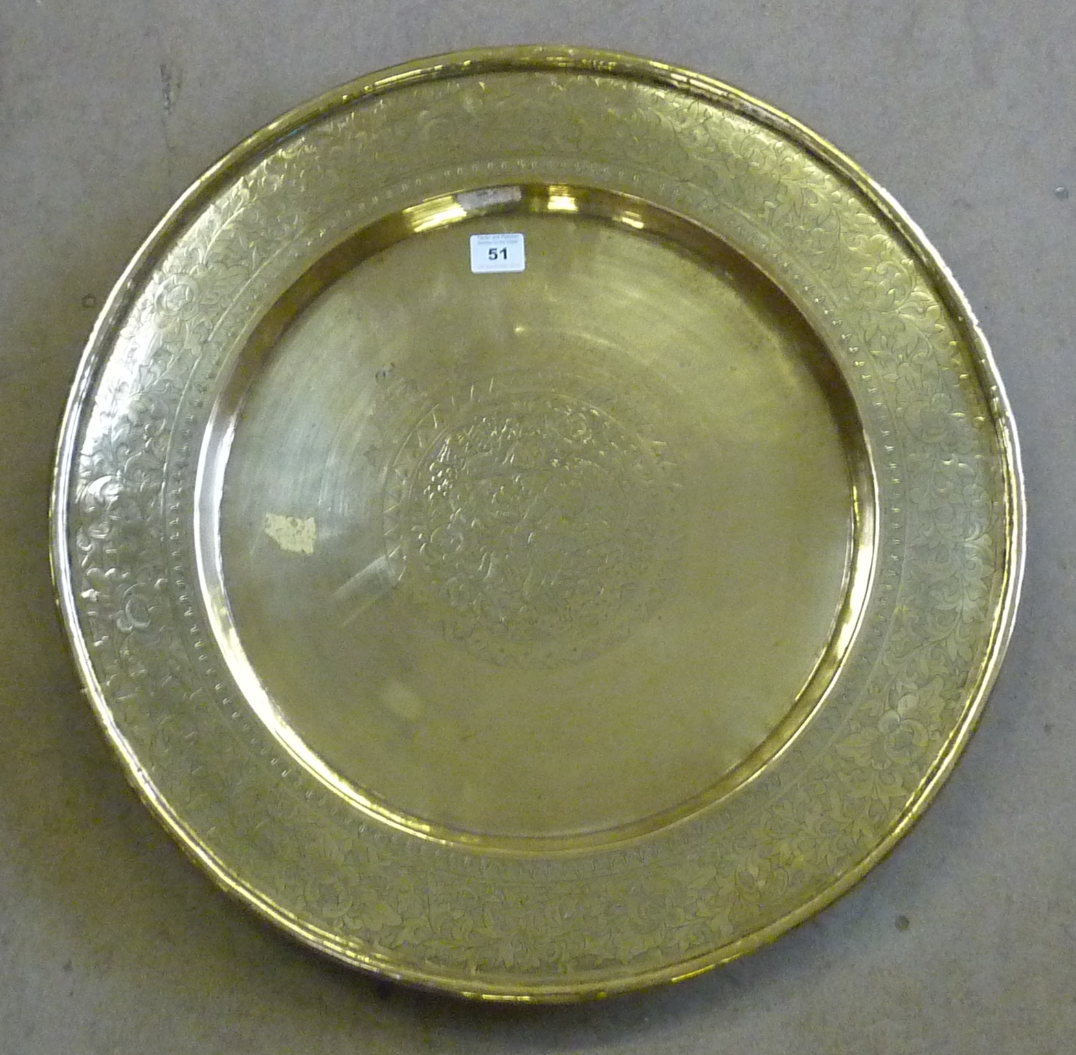 A late 19th/early 20th Century polished brass Eastern style Dish, central engraved decoration of