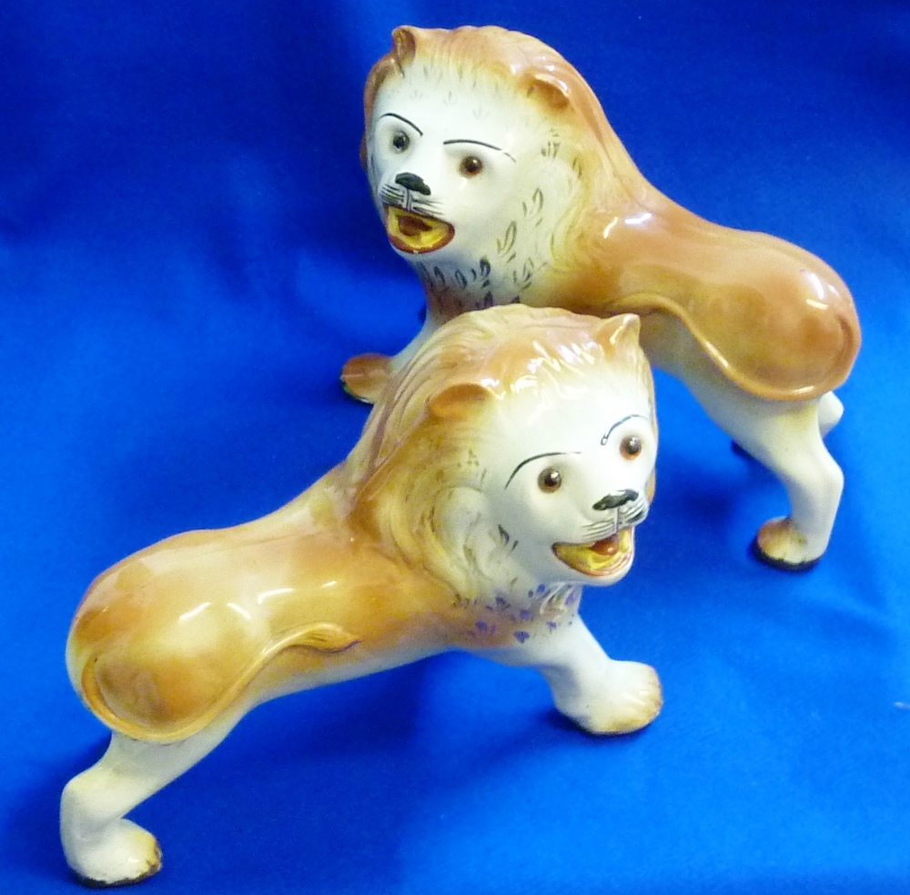 A very large pair of opposing Staffordshire male lions, each in menacing fashion facing and with