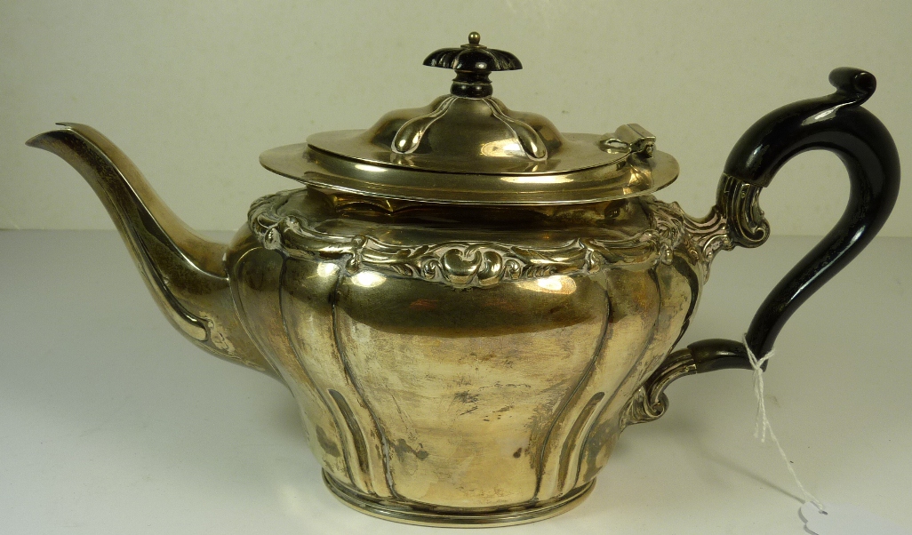 An Edwardian silver teapot having hinged domed cover with ebony finial, scrolling foliate