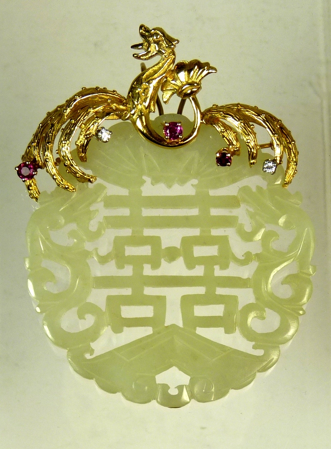 A Chinese pierced and carved jade pendant on decorative gold dragon brooch mount (unmarked tests as
