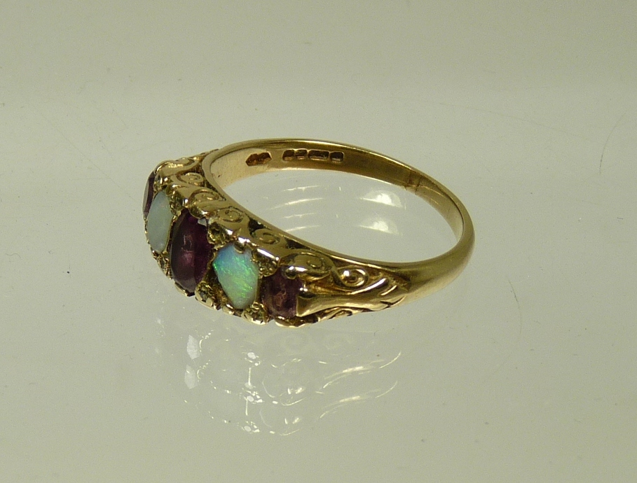 A Victorian 9ct gold opal and red stone ring with scroll mount and in Spink and Son box, 3.9g