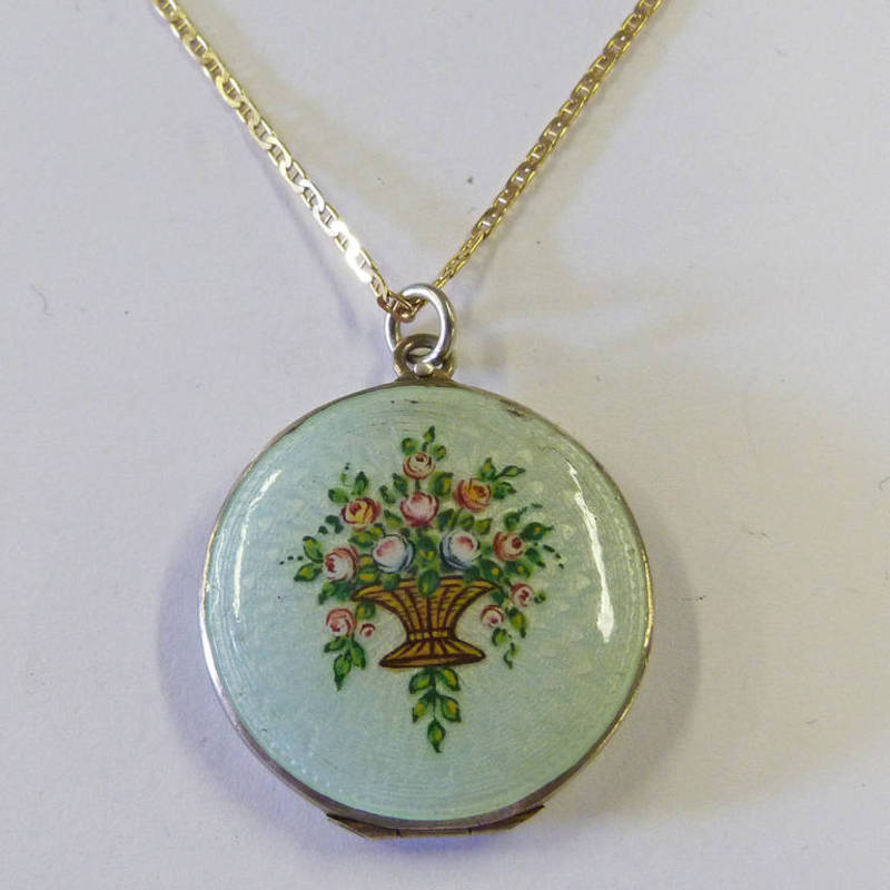 CIRCULAR LOCKET WITH GILDED INTERIOR, DECORATED WITH PALE GREEN ENAMEL & BASKET OF FLOWERS ON 9CT