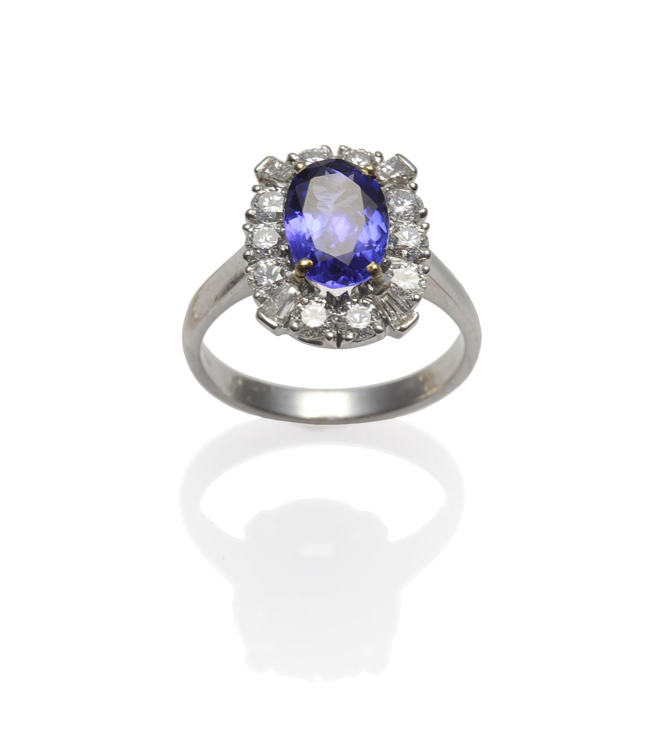 An 18 Carat White Gold Tanzanite and Diamond Cluster Ring, the oval cut tanzanite within a border