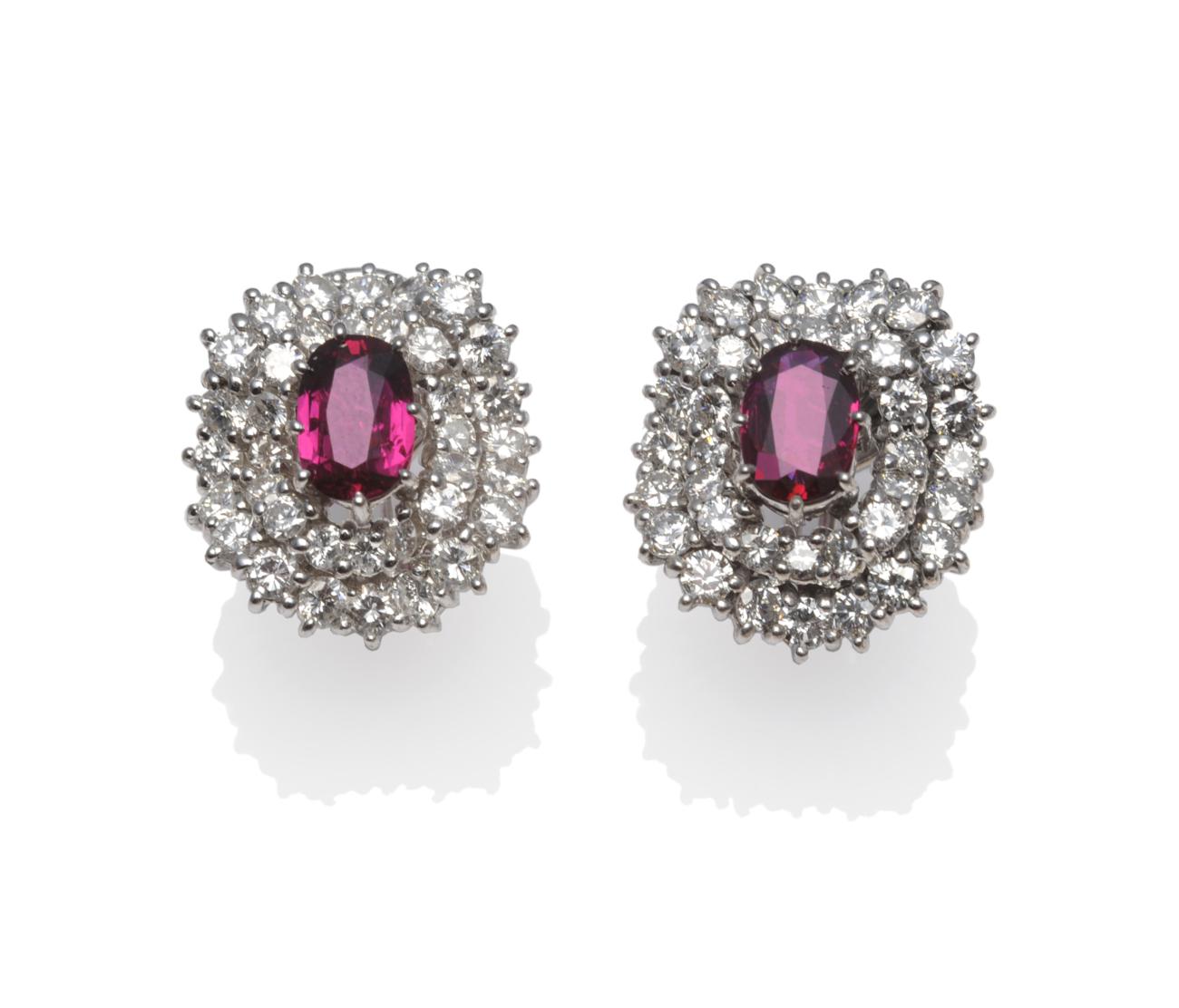 A Pair of Ruby and Diamond Cluster Earrings, an oval cut ruby centres two undulating borders set