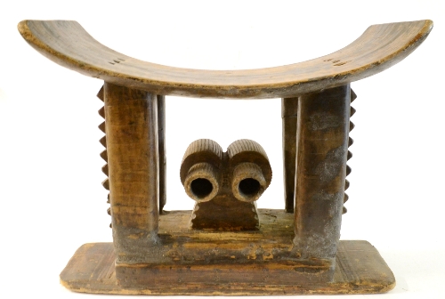 An Asante Wood Stool, Ghana, carved from one block of wood, with curved seat on four rectangular