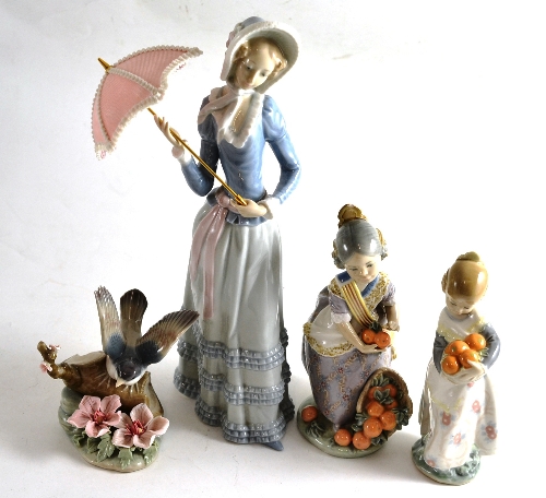 Four Lladro figures comprising a figure of a young lady with a parasol, two children with oranges