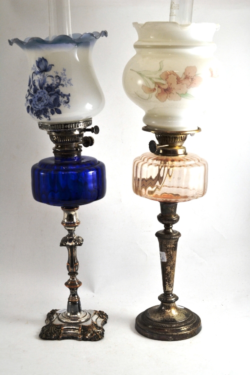 Two silver plated oil lamps one with a blue glass font