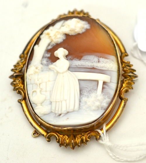 A Victorian cameo brooch, depicting a maiden collecting water beneath a tree, in a fancy frame,