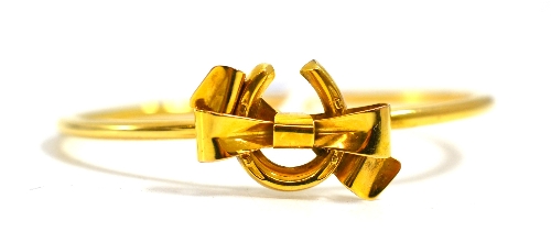 A horseshoe and bow bangle, stamped `15ct`, cased