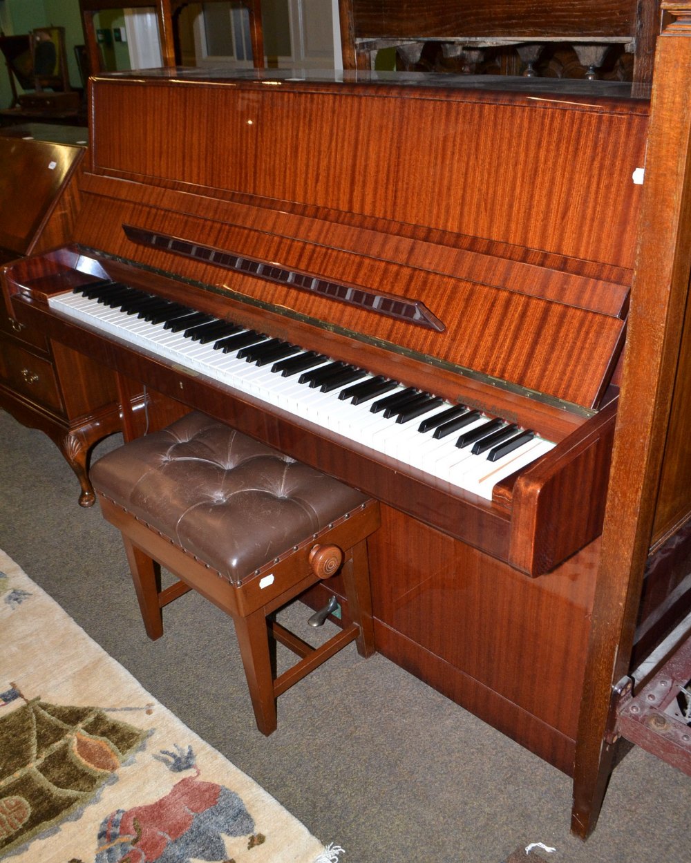 A mahogany upright piano with overstrung iron frame by August Forster with piano stool