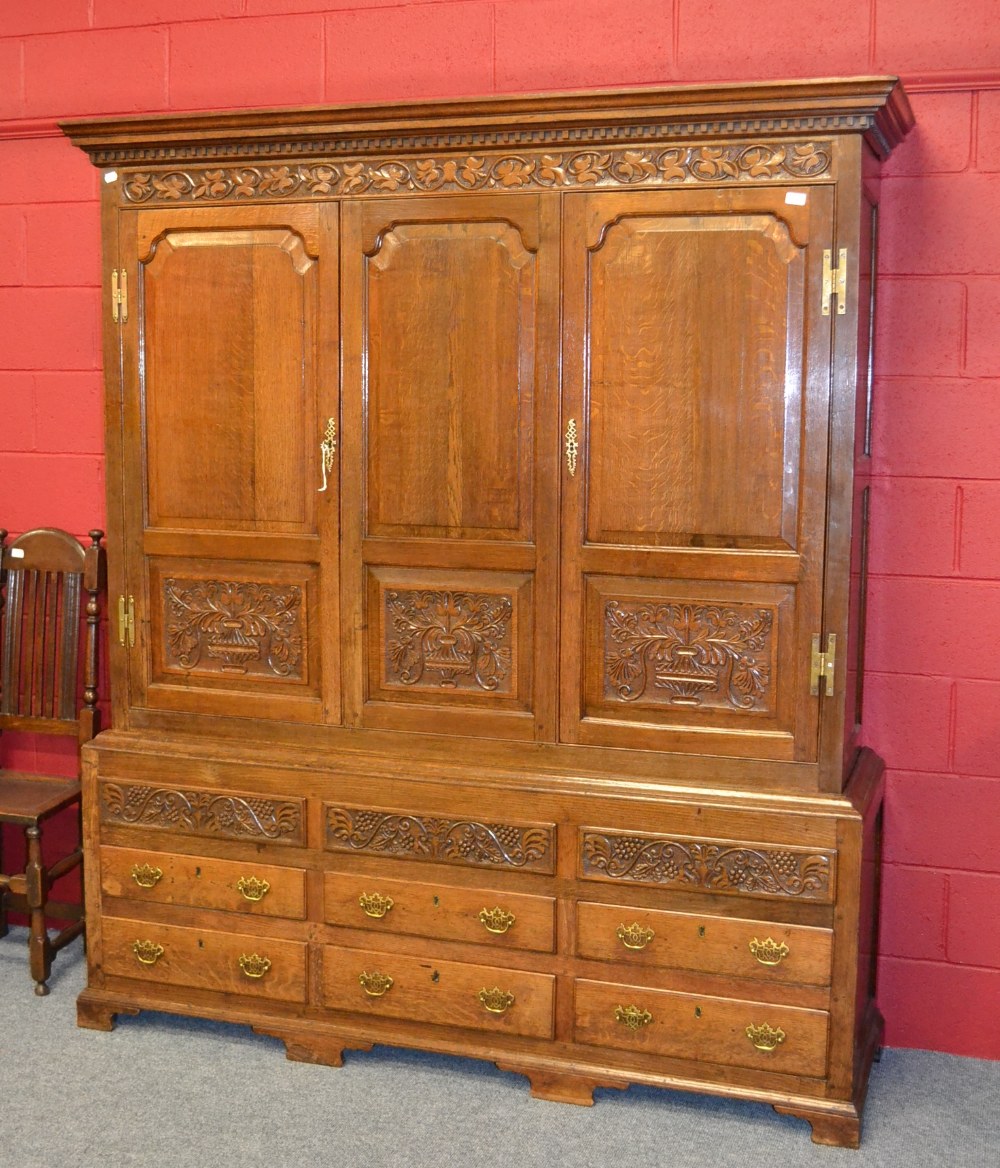 An English Joined Oak Press Cupboard, the bold cornice above a carved frieze with fielded panel