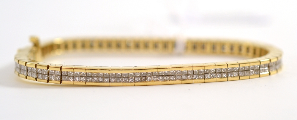A diamond bracelet, articulated links each comprise four princess cut diamonds, in a yellow channel