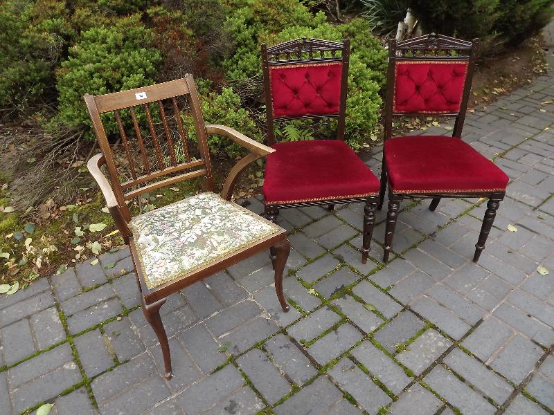An Edwardian armchair and two red upholstered dining chairs