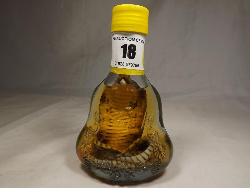 An unusual bottle of liquor containing a small cobra snake, sealed with contents, from Cambodia,