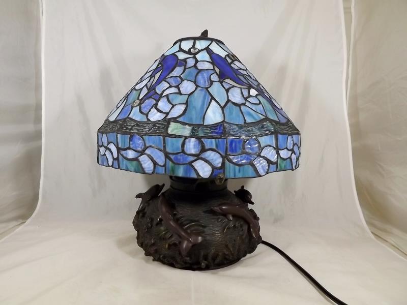 A Tiffany style table lamp, the base with relief decoration depicting dolphins, approx 38cm (h)