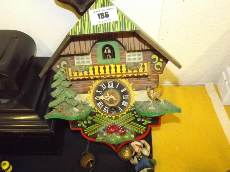 A Black Forest chalet style cuckoo clock, brightly painted with the pendulum in the form of a '