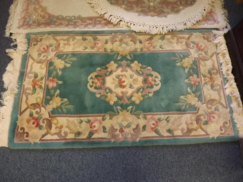 A pure wool rug with a floral design on a green and cream ground, 135cm x 69cm
