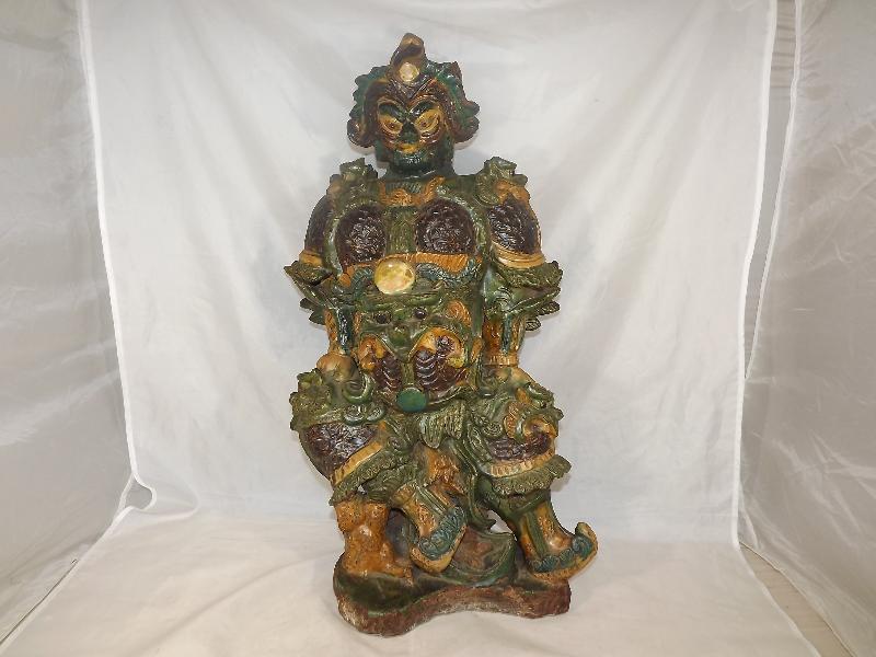 A Chinese Ming Sancai glazed pottery figure of a Guardian, in shades of green, yellow and brown