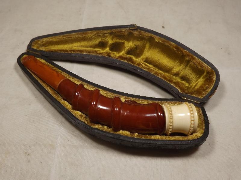 A amber coloured cheroot holder with meerschaum mount and relief serpentine decoration, cased