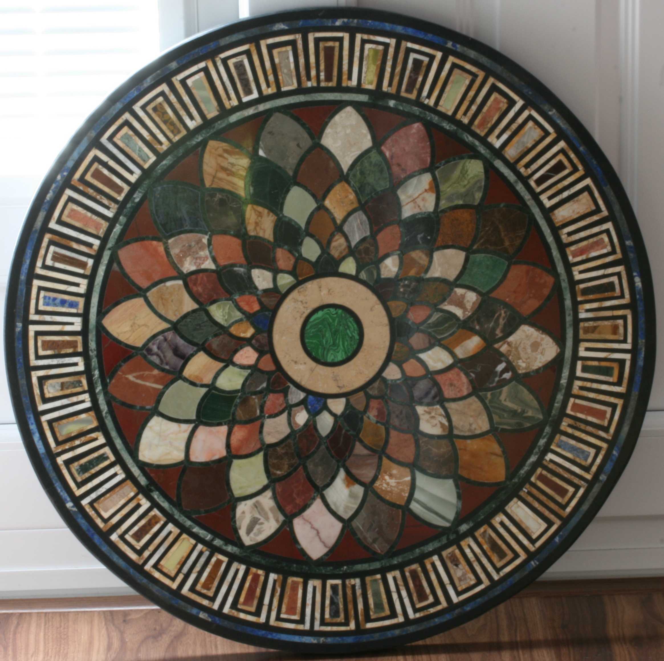 A Specimen Marble Table. Early 20th century. Of circular form. The black marble base inlaid with a