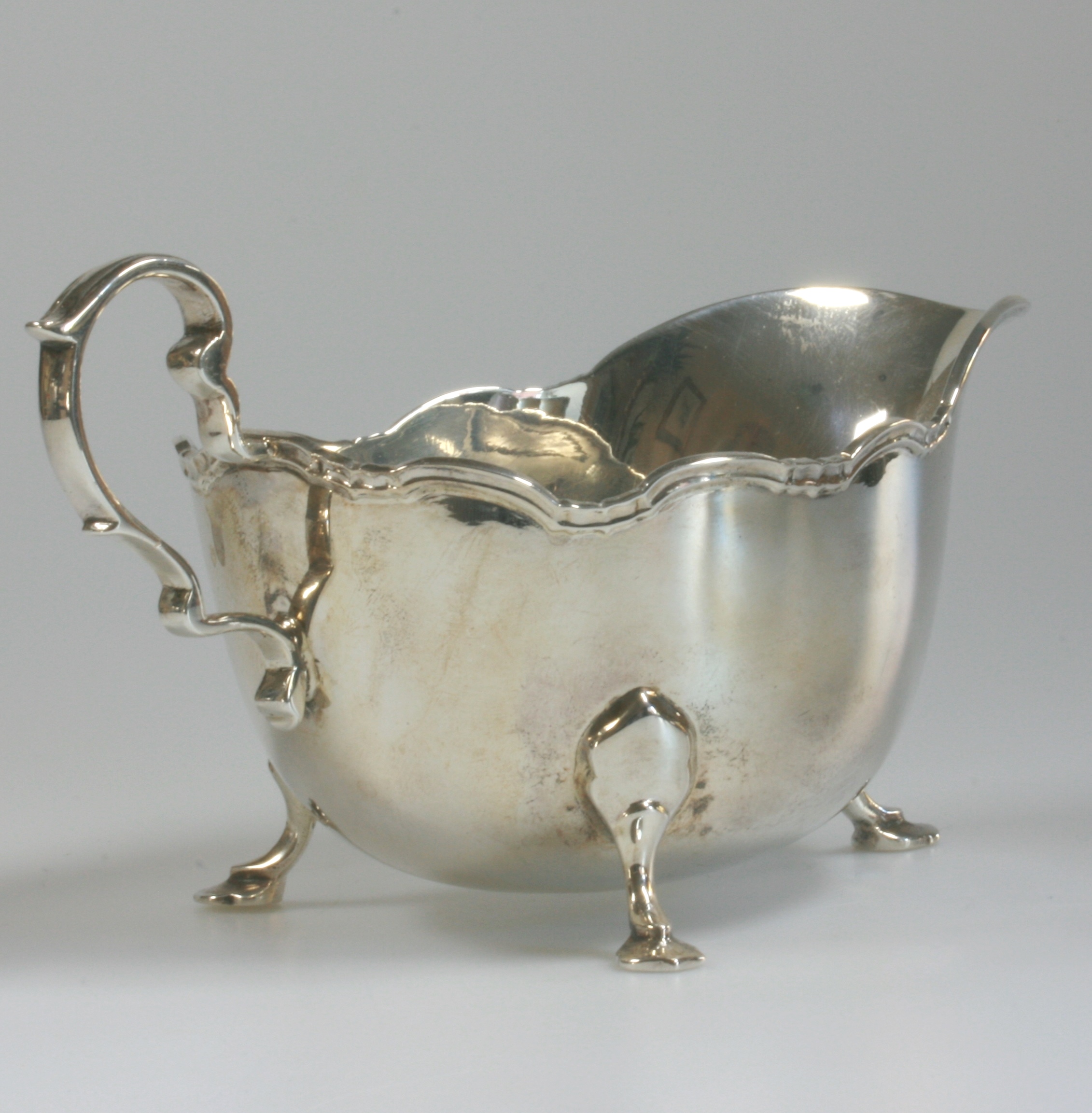 A George V Silver Sauce Boat. C J Vander. Sheffield, 1935. On three hoof feet with scroll rim and