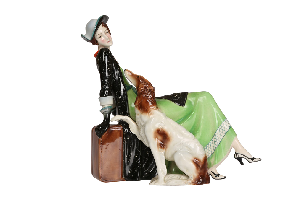 An Art Deco Katzhutte porcelain figure, modelled as a lady sitting on her luggage with a Borzoi