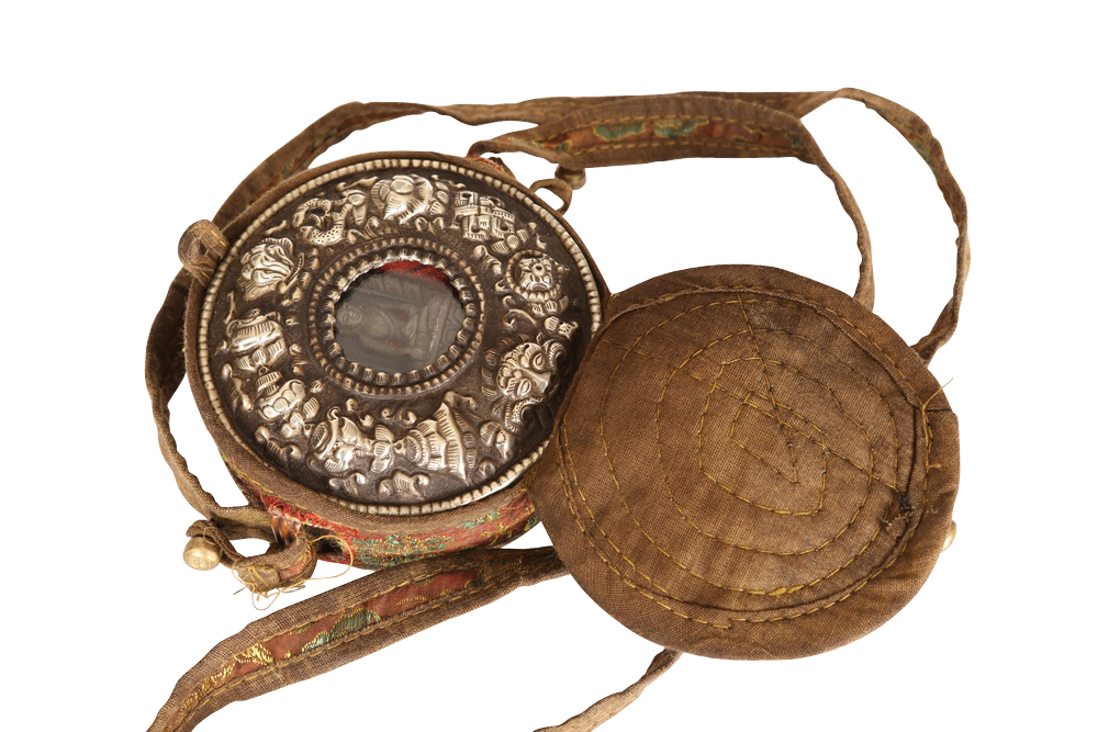 A Tibetan Monk's travelling shrine, centred with a deity within an embossed white-metal surround, in