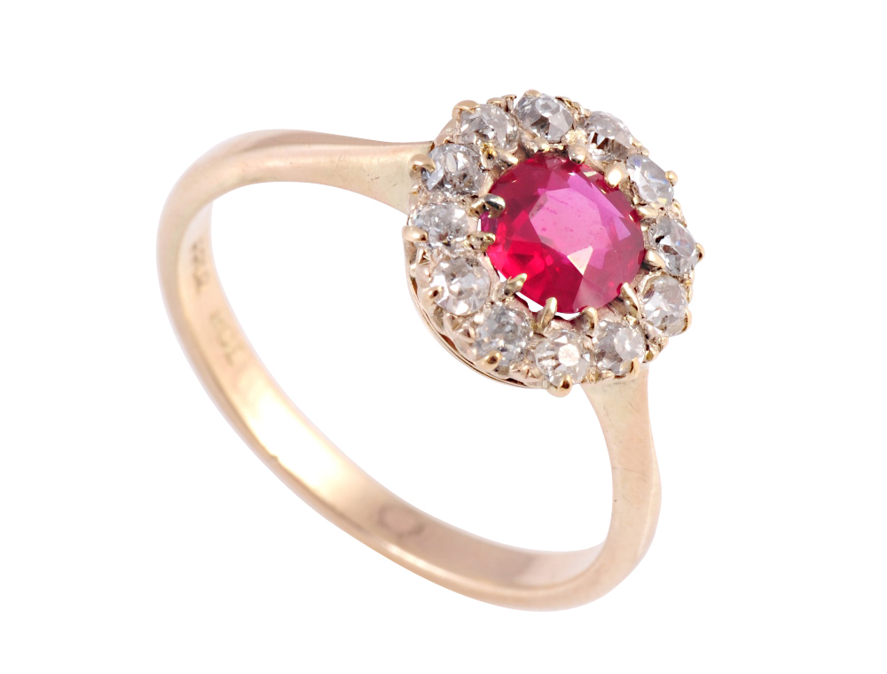 A ruby and diamond ring, circa 1900, the round mixed cut ruby twelve claw set within a bezel of