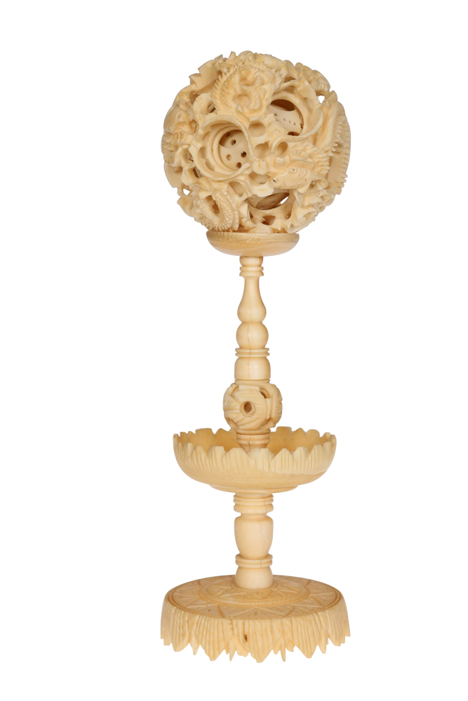 A Chinese carved ivory puzzle ball on stand, 19th Century, the ball characteristically carved with