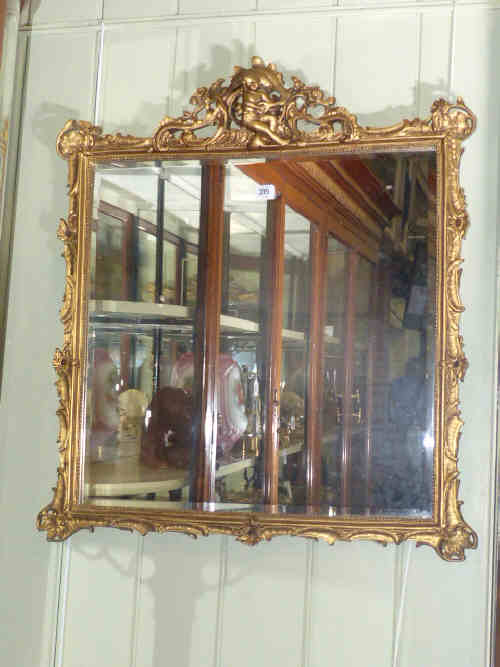 Gilt framed bevelled wall mirror with child musician crest, 81cm x 73cm