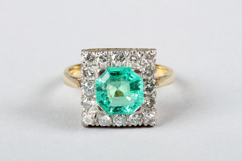 Emerald and diamond ring, 2 carat emerald surrounded with small diamonds in a square mount, 18 carat