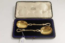 A pair of silver-gilt serving spoons, with engraved serpent stems, London 1901, cased.   CONDITION