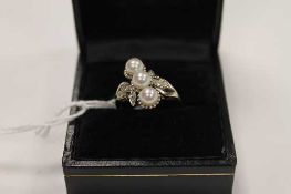 An 18ct white gold ring set with three pearls and diamond shoulders.   CONDITION REPORT:  Good