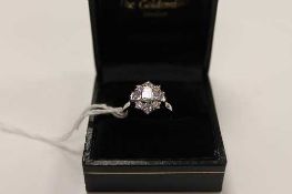 A platinum nine stone diamond cluster ring set with emerald, square and brilliant cut diamonds.