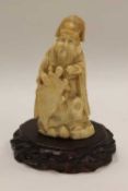 An early twentieth century carved ivory figure depicting a robed gentleman holding a turtle, on