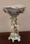 A continental porcelain encrusted comport surmounted with cherubs, height 46 cm.     CONDITION