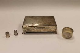 A silver cigar box, together with a silver napkin ring and two silver thimbles. (4)   CONDITION