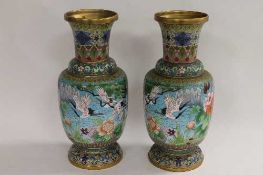A pair of early twentieth century cloisonne vases, decorated with birds in flight amongst foliage,