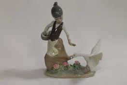 A Lladro figure - A lady playing with a goose, together with three other figures of geese, all