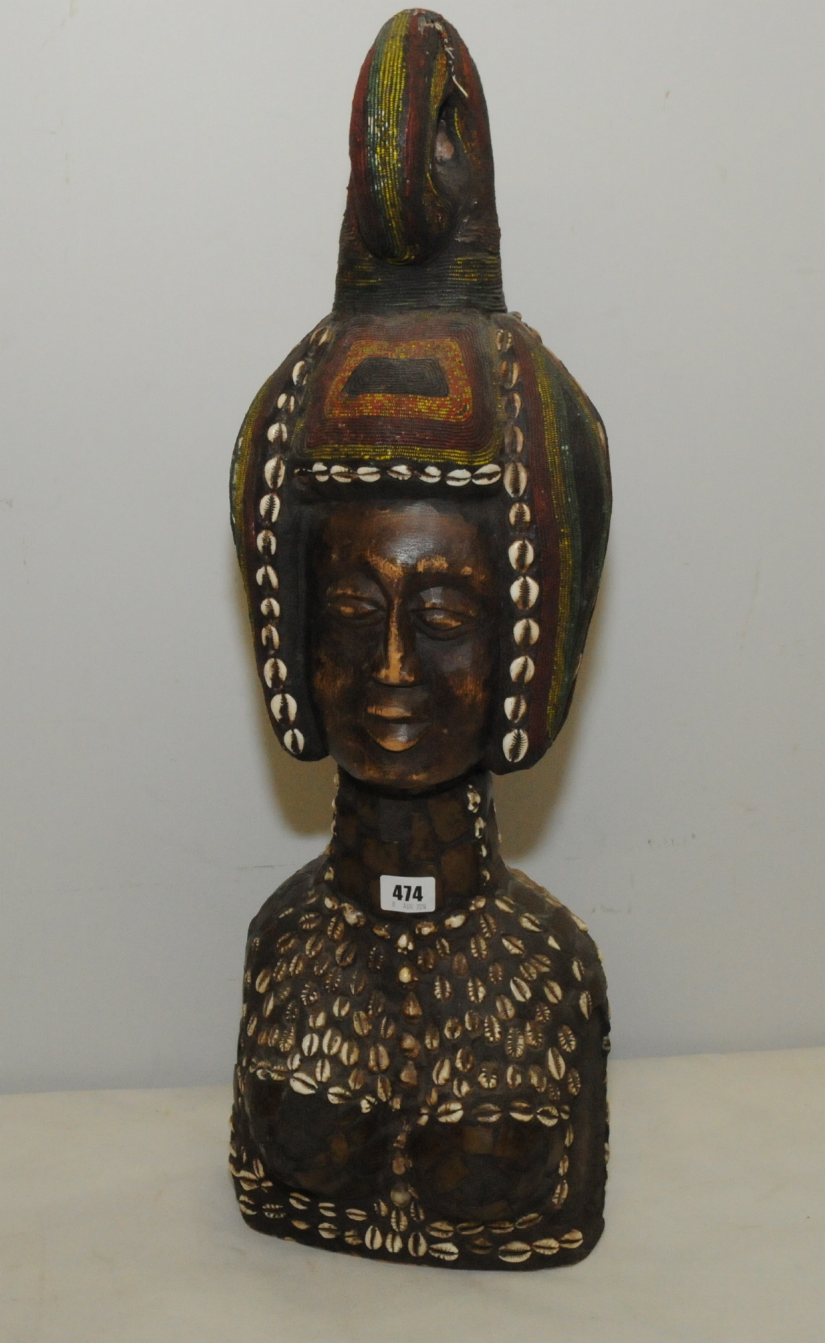 Large African carved bust of a woman wearing a scrolled head dress, profusely decorated with