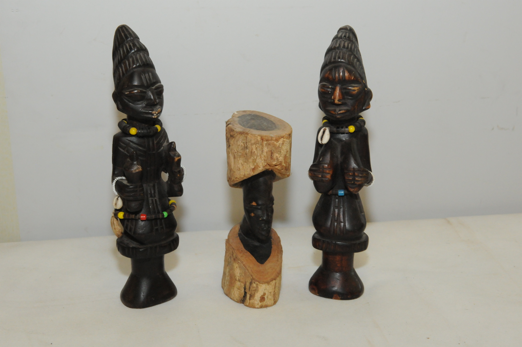 Two stained wood carved African stylised figures, one male, one female, each decorated with