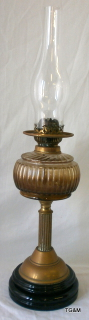 A tall brass oil lamp with glass body to include glass flume