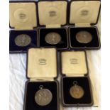 Five cased white metal medallions from the Hampshire Regiment for boxing and running