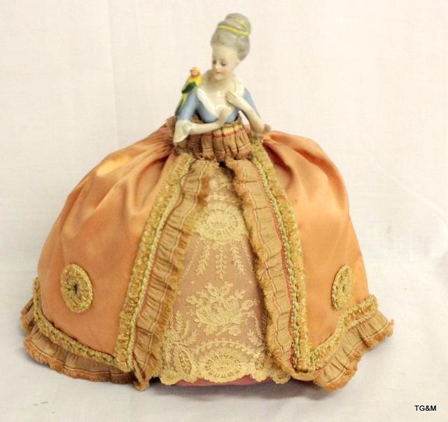 A Victorian German porcelain bodied door stop in original Victorian silk and lace dress wear, 26cm