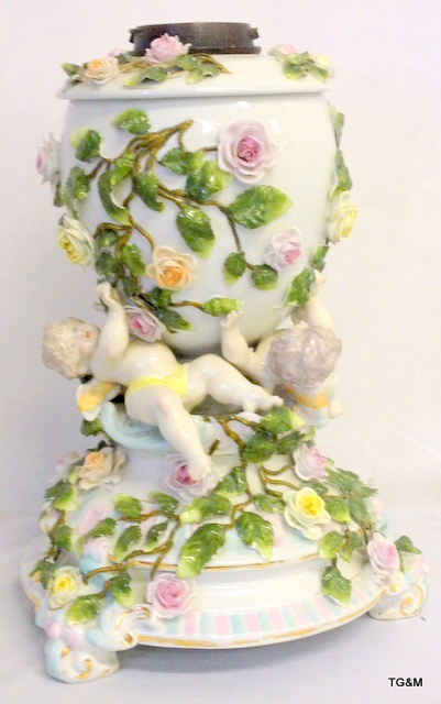 A Victorian Sitzendorf style porcelain oil lamp surmounted with cherubs and flowers which has been