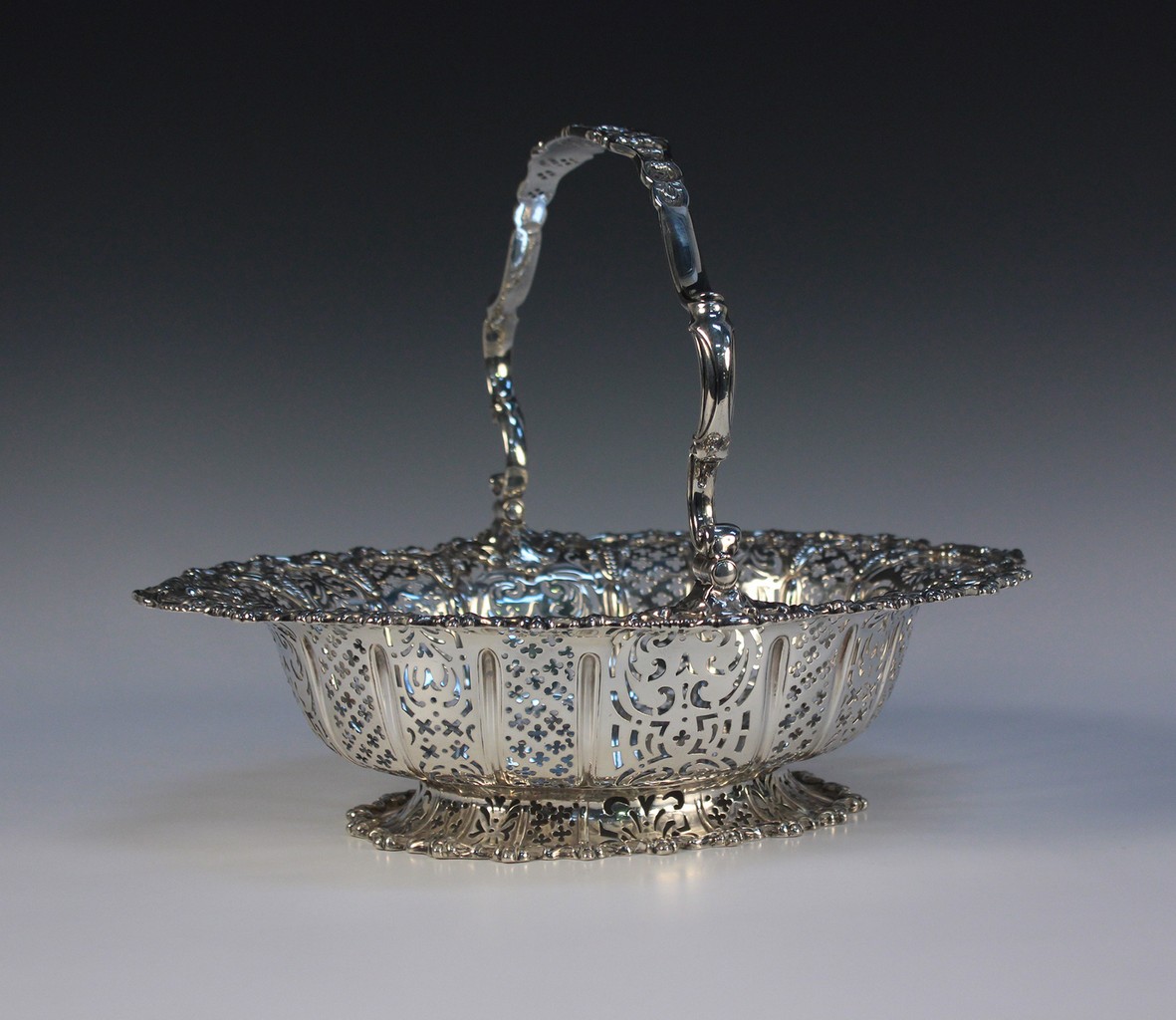 A Victorian silver oval cake basket, the overhead scroll handle cast with lattice panels and