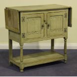 An early 20th Century limed oak side cabinet, the drop-flap top above a pair of carved linenfold