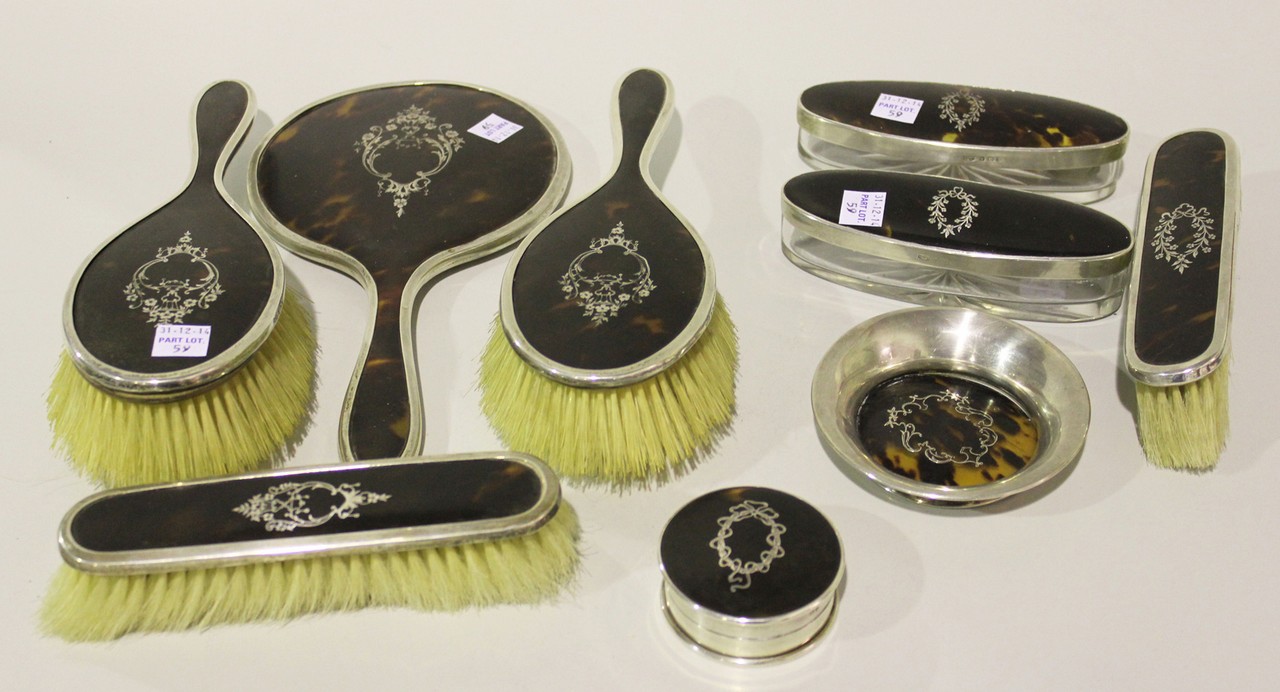 A George V silver and tortoiseshell eight piece dressing table set with piqué inlaid floral