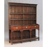 An 18th Century oak dresser, the moulded pediment and shelf back above three drawers and a pot